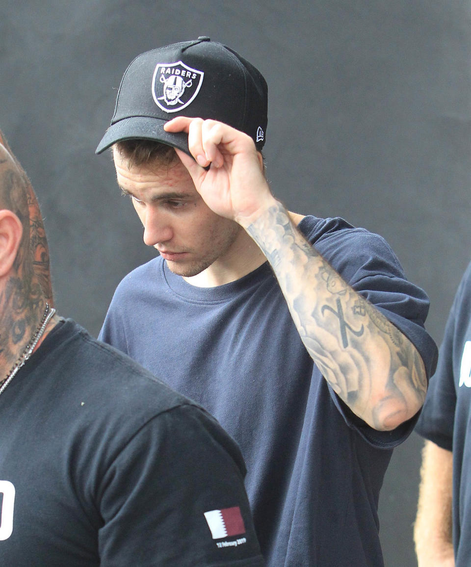 Justin Bieber lifts his Raiders cap, reveals tattoos on his arm and walks with security guards
