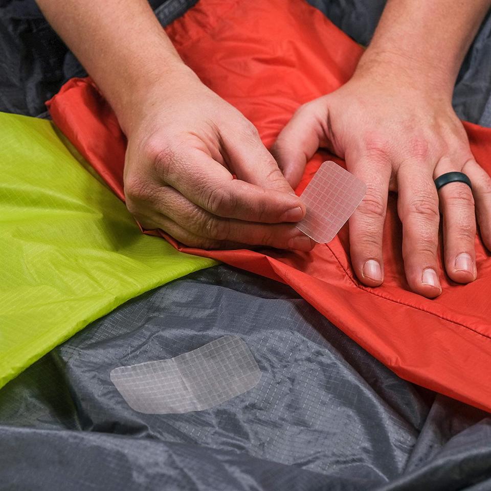 A person putting patches on a tent