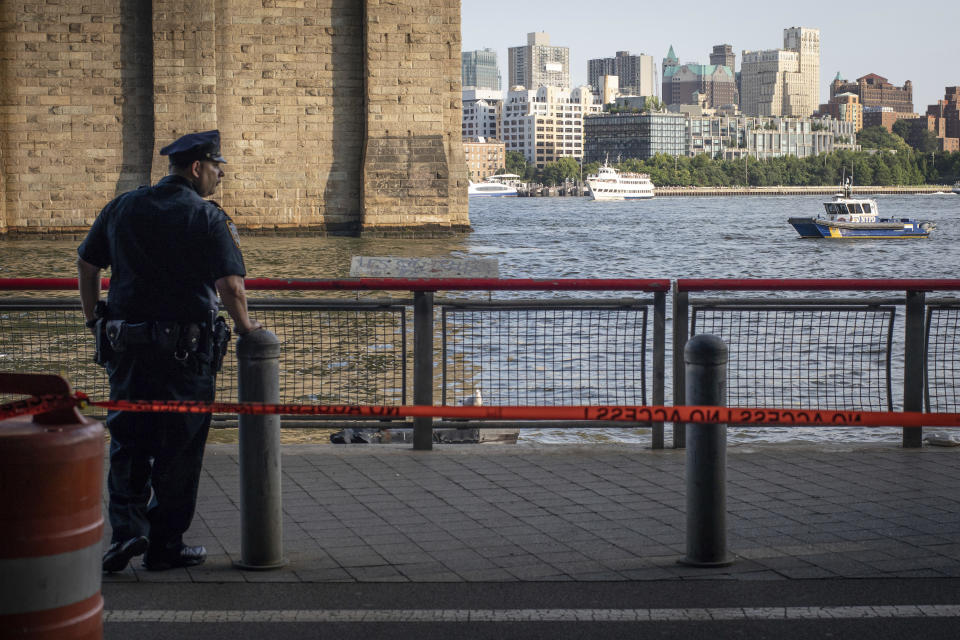 FILE - In this Aug. 5, 2018, file photo, a New York Police Department officer stands guard as authorities investigate the death of a baby boy who was found floating in the East River near the Brooklyn Bridge in the Manhattan borough of New York. A Bronx father hopped a plane to Thailand after carrying his dead 7-month-old baby around New York City in a backpack and tossing the boy's body into the river and other tourist hotspots, police said Wednesday. (AP Photo/Robert Bumsted, File)