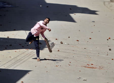 A Kashmiri protester throws a stone towards Indian security personnel during a demonstration against the plan to resettle Hindus, in Srinagar April 10, 2015. REUTERS/Danish Ismail