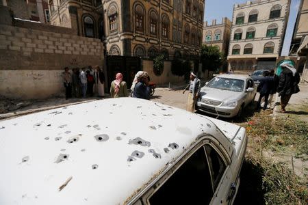 People gather near a car damaged by a mortar shell during fighting between Shi'ite Houthi militants and government forces in Sanaa September 19, 2014. REUTERS/Khaled Abdullah