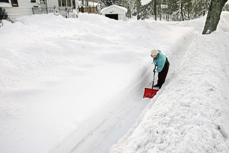 Ethel O'Leary is dwarfed by snowbanks as she helps clear the sidewalk in front of her house after her nephew went over it with the snowblower in Duluth