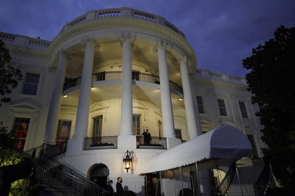 President Donald Trump salutes from the Blue Room Balcony as he returns to the White House Monday, Oct. 5, 2020, in Washington, after leaving Walter Reed National Military Medical Center, in Bethesda, Md. Trump announced he tested positive for COVID-19 on Oct. 2. (AP Photo/Alex Brandon)