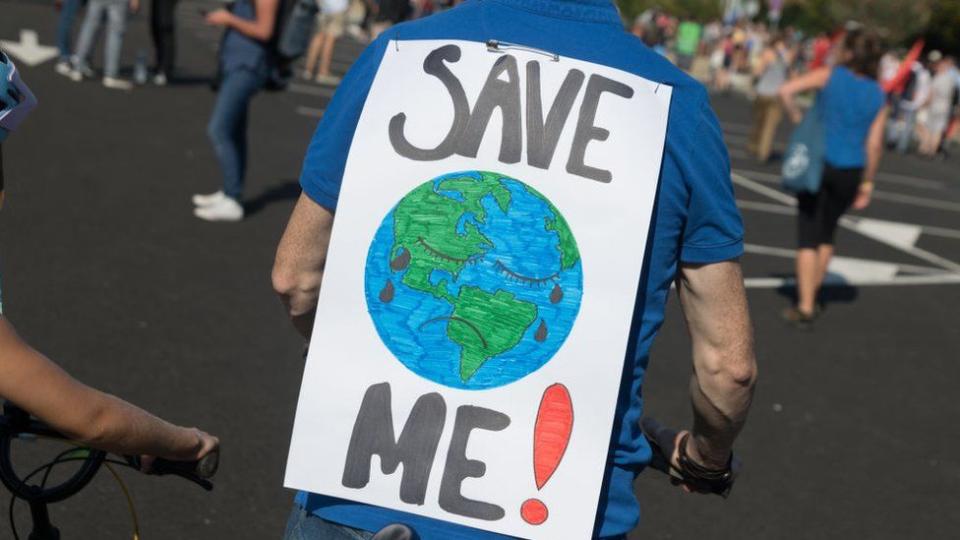 Un hombre con un cartel con un dibujo de la tierra