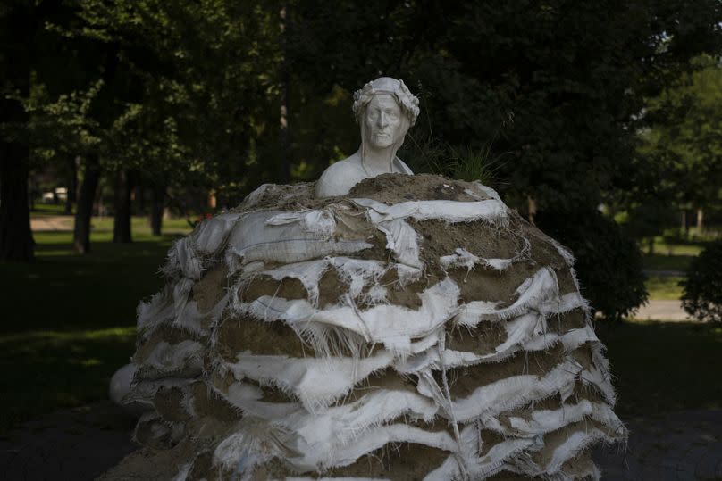 Sacos de arena apilados alrededor del Monumento a Dante Alighieri para proteger la estatua de un posible bombardeo ruso en Kiev, julio de 2023.