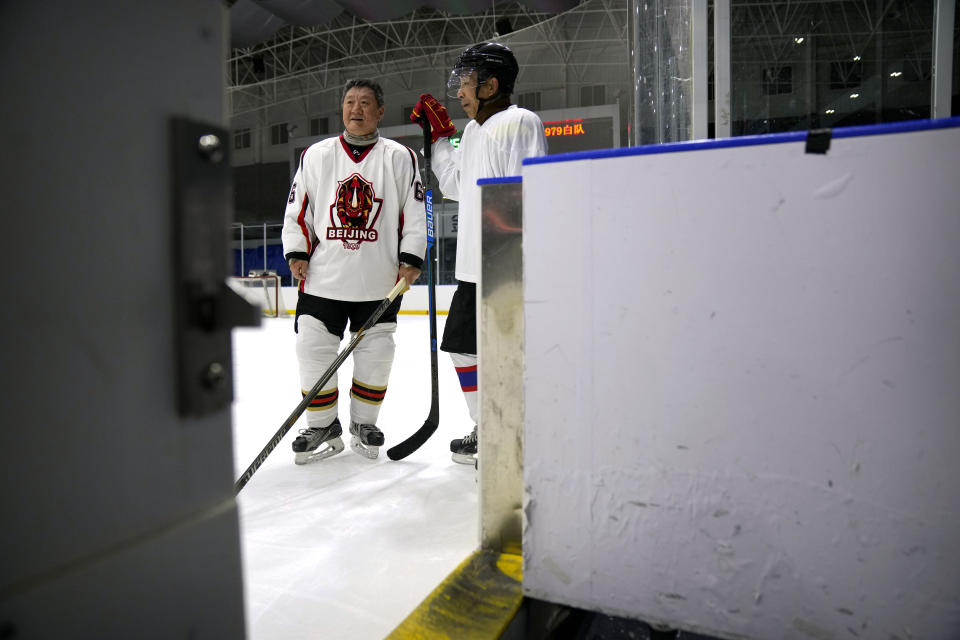 Members of the "1979" hockey club stand on the ice during a break between periods in a hockey match at a rink in Beijing, Wednesday, Jan. 12, 2022. Spurred by enthusiasm after China was awarded the 2022 Winter Olympics, the members of a 1970s-era youth hockey team, now around 60 years old, have reunited decades later to once again take to the ice. (AP Photo/Mark Schiefelbein)