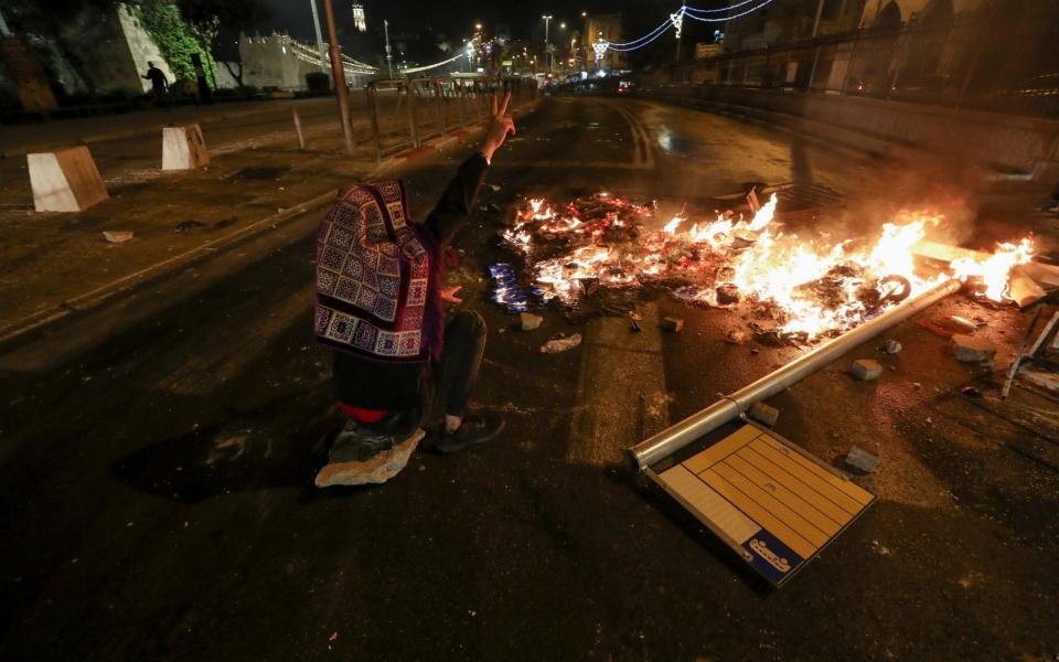 A Palestinian sitting next to a burning barricade flashes a ''V'' sign during clashes with Israeli police, as the Muslim holy fasting month of Ramadan continues, in Jerusalem - Reuters/Reuters