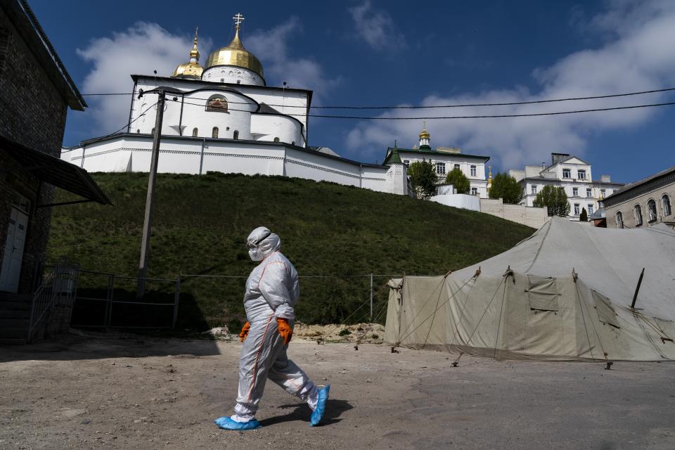 In this photo taken on Friday, May 1, 2020, a nurse wearing a special suit to protect against coronavirus, walks at a hospital with the Pochaiv Lavra Orthodox monastery in Pochaiv, Ukraine. Ukraine's troubled health care system has been overwhelmed by COVID-19, even though it has reported a relatively low number of cases. (AP Photo/Evgeniy Maloletka)