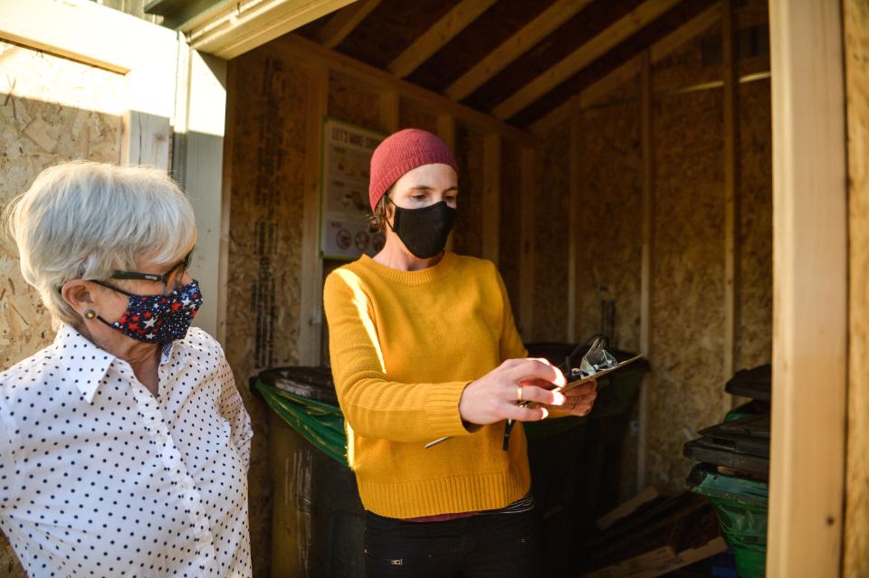 Kiera Bulan, Sustainability Coordinator at the Office of Sustainability with the City of Asheville, speaks with resident Diane Bruno about the pickup process for the Food Scrap Shed on December 15, 2021.