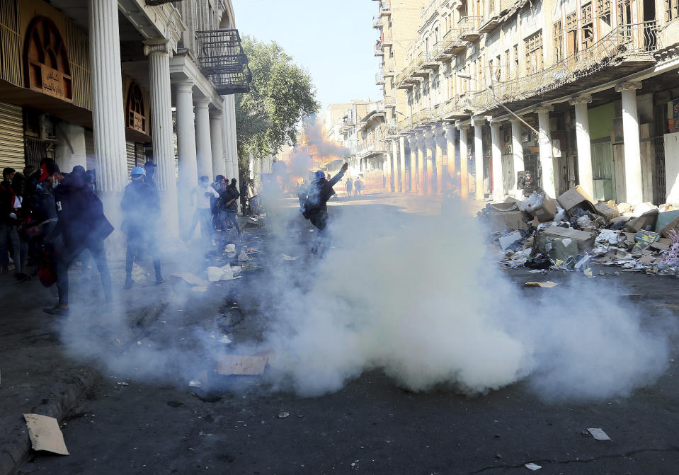 Riot police fire tear gas while blocking al-Rashid Street during clashes with anti-government demonstrators in Baghdad, Iraq, Friday, Nov. 22, 2019. Iraq's massive anti-government protest movement erupted Oct. 1 and quickly escalated into calls to sweep aside Iraq's sectarian system. Protesters occupy several Baghdad squares and parts of three bridges in a standoff with security forces. (AP Photo/Hadi Mizban)JA