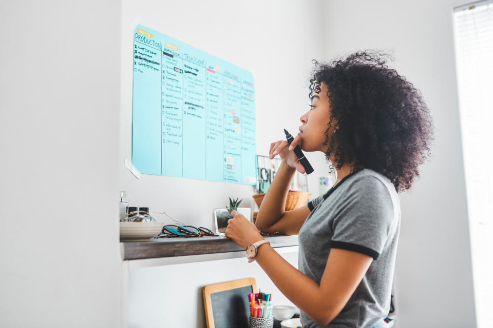 Person looking at a board with post-it notes, holding a pen, possibly planning or organizing tasks