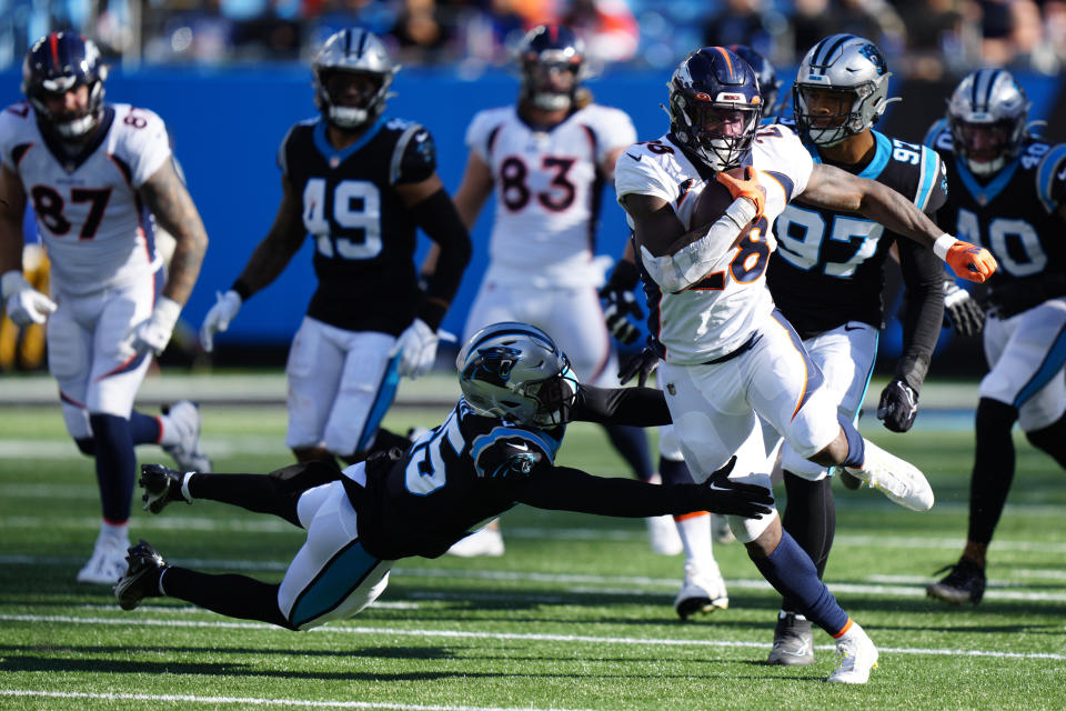 Denver Broncos running back Latavius Murray runs past Carolina Panthers safety Xavier Woods during the first half of an NFL football game between the Carolina Panthers and the Denver Broncos on Sunday, Nov. 27, 2022, in Charlotte, N.C. (AP Photo/Jacob Kupferman)