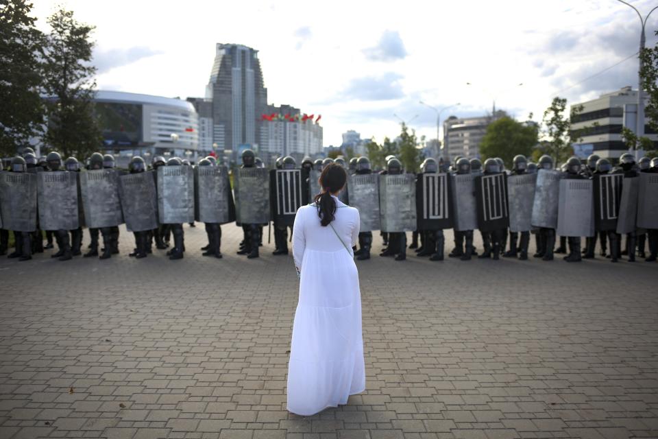 A woman wearing white, stands in front of a riot police line during a Belarusian opposition supporters' rally protesting the official presidential election results in Minsk, Belarus, Sunday, Sept. 13, 2020. Protests calling for the Belarusian president's resignation have broken out daily since the Aug. 9 presidential election that officials say handed him a sixth term in office. (TUT.by via AP)