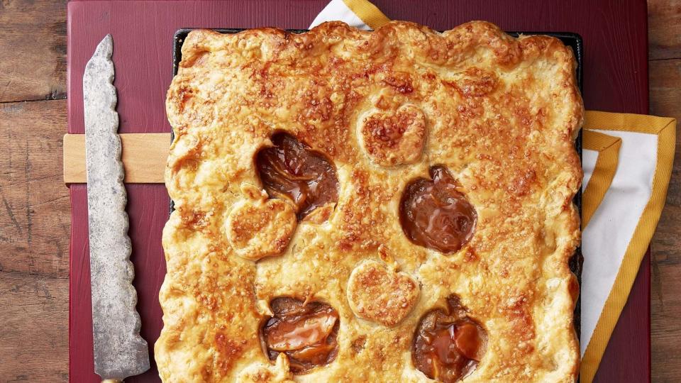 caramel apple slab pie with apple shaped cut outs in the top crust and served on a wooden serving board