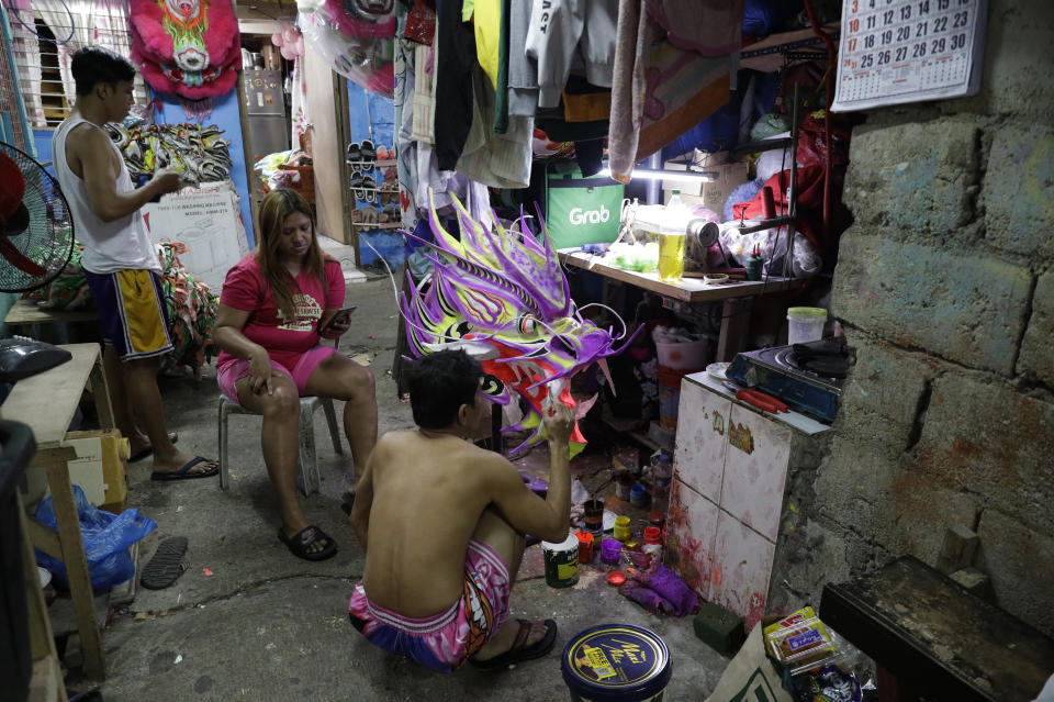 Robert Sicat paints a dragon head as members of a Dragon and Lion dance group seek other ways to earn a living at a creekside slum in Manila's Chinatown, Binondo, Philippines on Feb. 3, 2021. The Dragon and Lion dancers won't be performing this year after the Manila city government banned the dragon dance, street parties, stage shows or any other similar activities during celebrations for Chinese New Year due to COVID-19 restrictions leaving several businesses without income as the country grapples to start vaccination this month. (AP Photo/Aaron Favila)