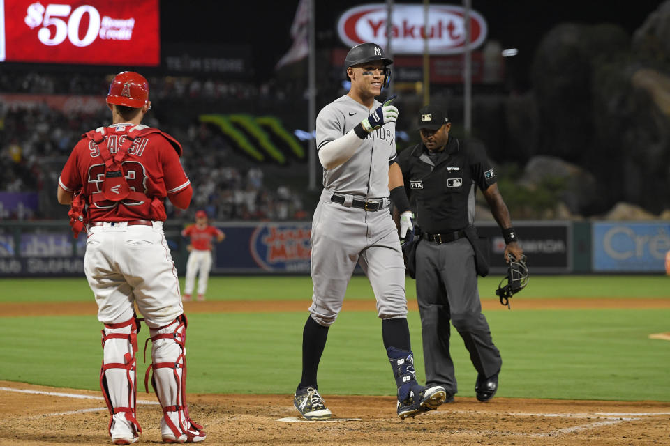 New York Yankees' Aaron Judge, center, gestures as he scores after hitting a three-run home run while Los Angeles Angels catcher Max Stassi, left, watches along with home plate umpire Alan Porter during the fourth inning of a baseball game Tuesday, Aug. 30, 2022, in Anaheim, Calif. (AP Photo/Mark J. Terrill)