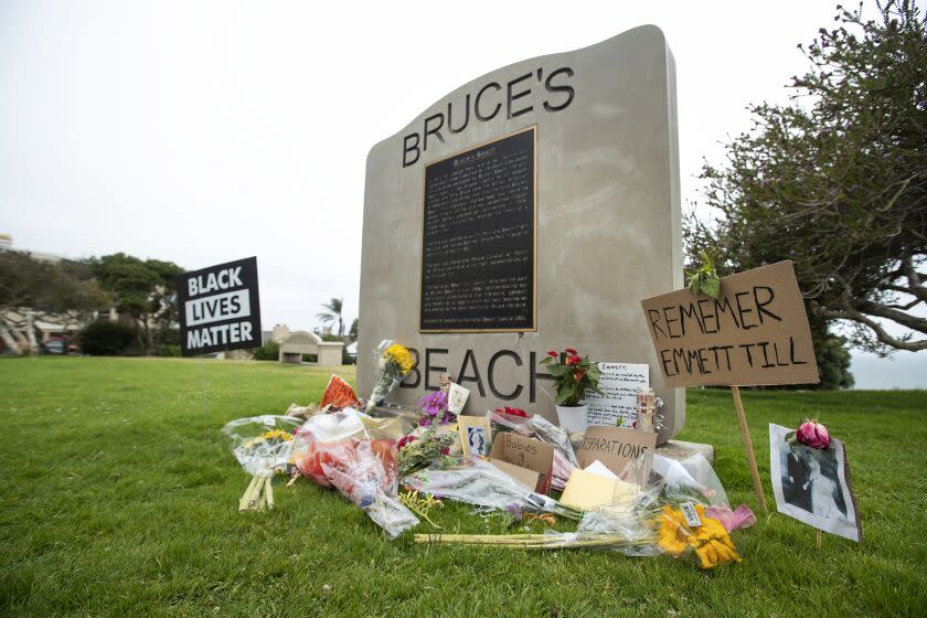 MANHATTAN BEACH, CA -JULY 29, 2020: A photograph of Charles and Willa Bruce, right, is part of a memorial to Emmett Till, located in front of a commemorative plaque at Bruce's Beach, a park located in Manhattan Beach. Till was a 14-year-old African American who was lynched in Mississippi in 1955. Bruce's Beach used to be owned by Charles and Willa Bruce, one of the first prominent Black oceanfront homeowners (in the 1920's) but Manhattan Beach ran them out of town and erased/rewrote the history of what happened. A new generation of residents are now calling on the city to confront its racist past. Many have reclaimed the space in recent weeks to celebrate and honor the Black Lives Matter movement. (Mel Melcon / Los Angeles Times)