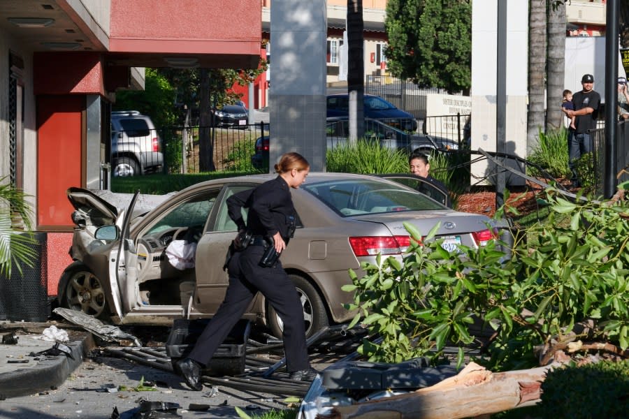 A Los Angeles Police Department officers assess an accident near downtown Los Angeles on Thursday, Oct. 6, 2016. The traffic accident left a vehicle overturned on a sidewalk and another smashed-up car in the drive-thru lane of a fast-food restaurant. (AP Photo/Richard Vogel)