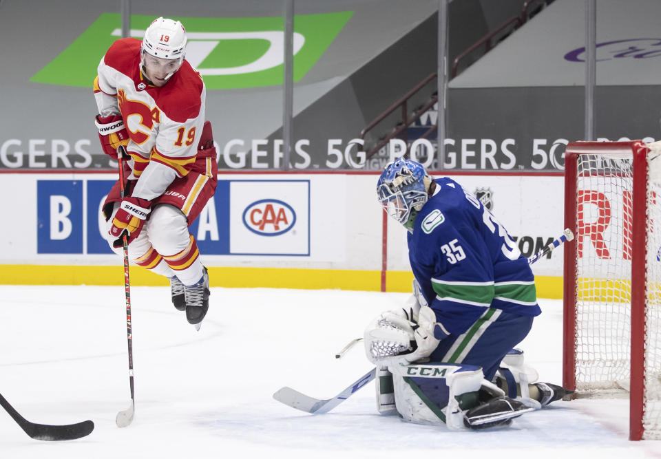 Calgary Flames' Matthew Tkachuk (19) jumps in front of Vancouver Canucks goalie Thatcher Demko, who makes a save during the first period of an NHL hockey game Saturday, Feb. 13, 2021, in Vancouver, British Columbia. (Darryl Dyck/The Canadian Press via AP)