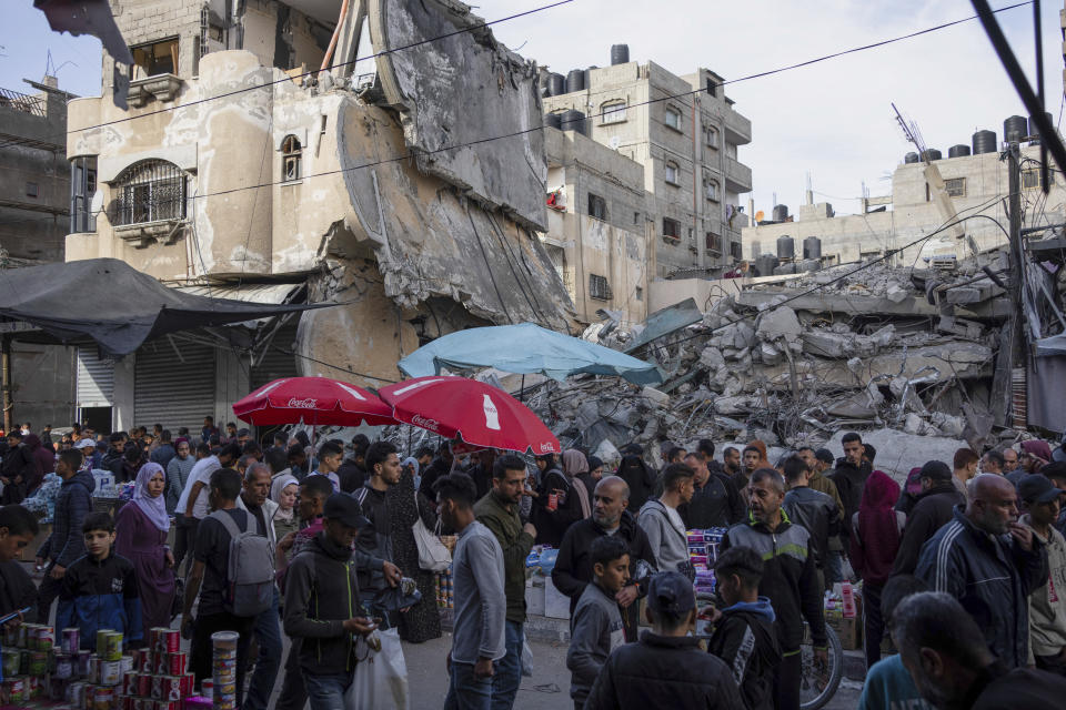 Palestinians buy food at a local market next to a destroyed residential building by the Israeli airstrikes, during the Muslim holy month of Ramadan, in Rafah, Gaza Strip, Thursday, March 14, 2024. (AP Photo/Fatima Shbair)