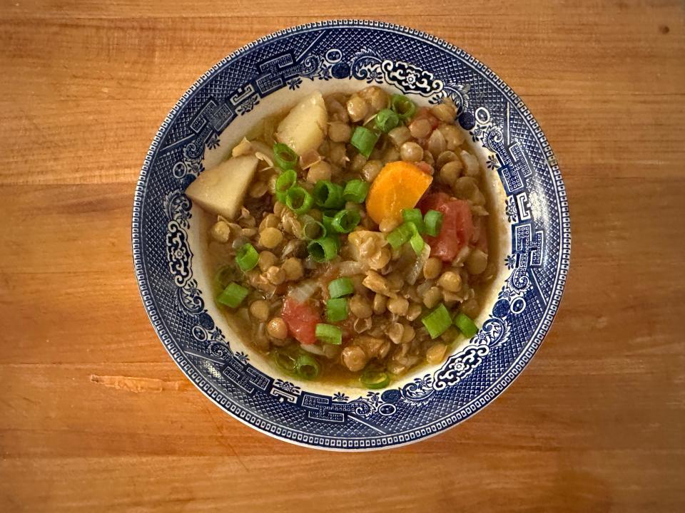 Bowl of lentil soup with scallions on top.