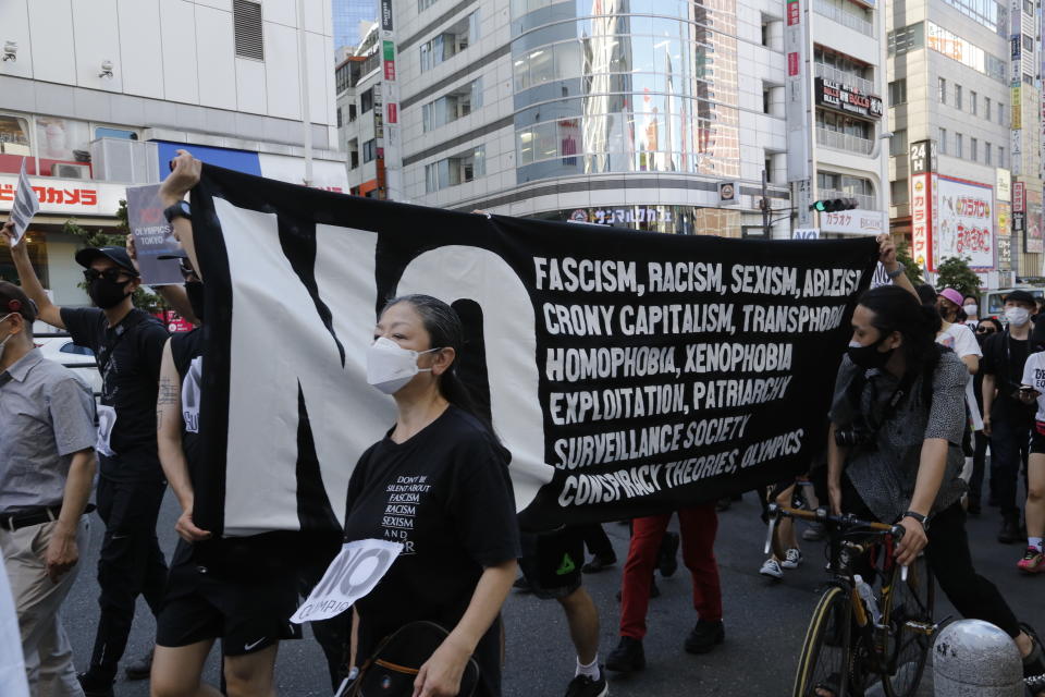 People march in Tokyo's Shinjuku shopping district Sunday, July 18, 2021, to protest against the Tokyo Olympics starting from July 23.(AP Photo/Yuri Kageyama)