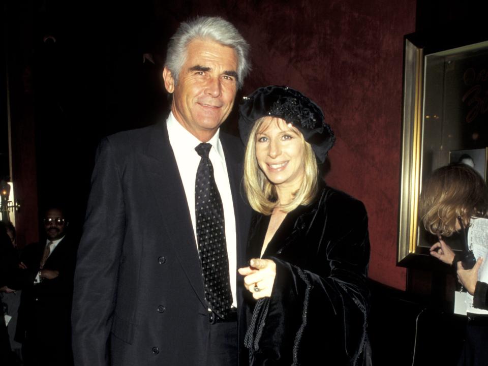 James Brolin, in a black suit, poses with Barbra Streisand, in a black velvet gown and hat, at a red carpet event in the '90s.