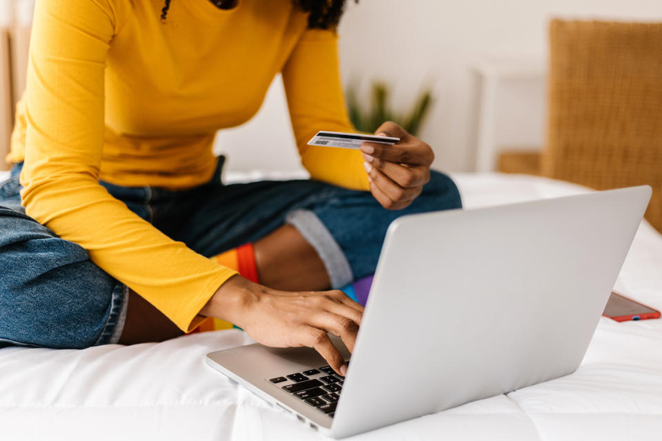 A woman using a computer with her credit card in her hand