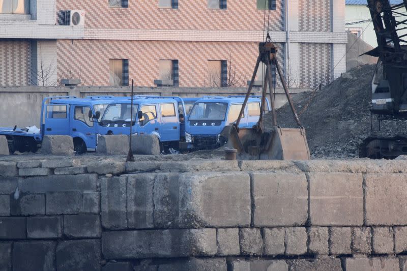 Trucks are parked next to a pile of coal on the bank of the Yalu River in Sinuiju