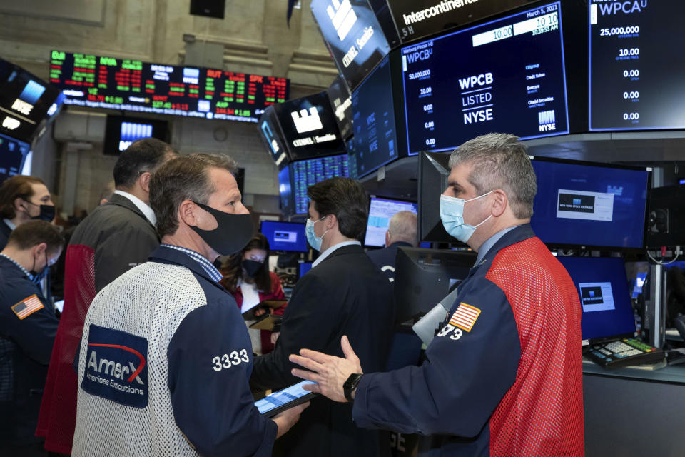 In this photo provided by the New York Stock Exchange, traders Robert Charmak and John Panin, foreground left and right, work on the floor, Friday, March 5, 2021, in New York. Stocks are swerving through another rocky ride Friday, as investors struggle to figure out what an encouraging report on the economy and the recent march higher for bond yields should mean for the market. (Nicole Pereira/New York Stock Exchange via AP)