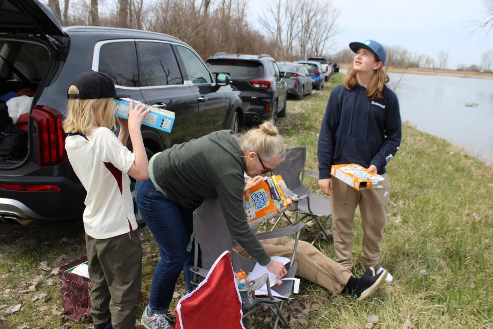 Clarkston residents Kristen and Robert Miner, center, and their grandsons, Liam, left, and Lars, created their own pinhole viewing cameras for Monday’s eclipse.