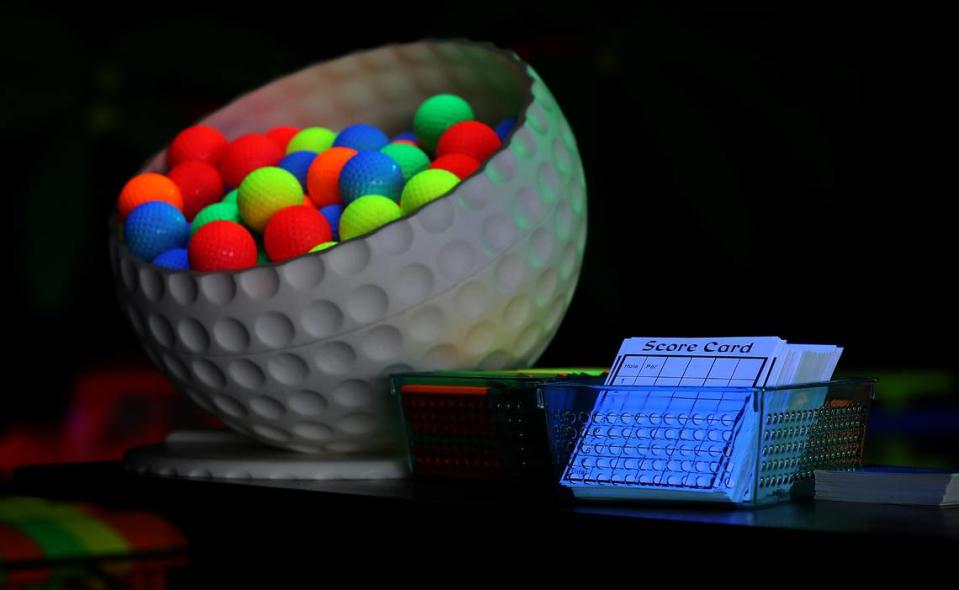 Score cards and bright colored golf ball sit on the counter of Let’s Glow Mini Golf.