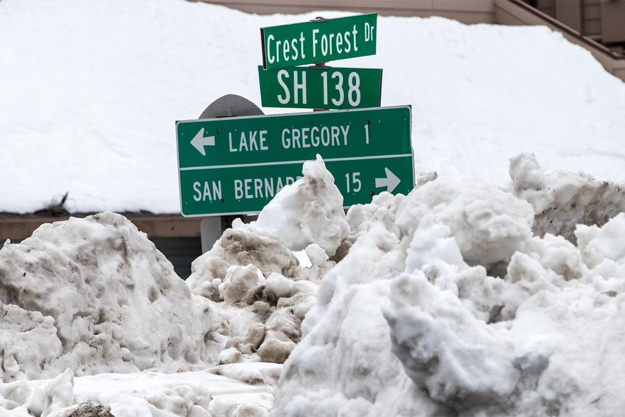 CRESTLINE, CA - MARCH 6, 2023: Street signs stick out from piles of snow off Highway 138 on March 6, 2023 in Crestline, California. (Gina Ferazzi / Los Angeles Times via Getty Images)