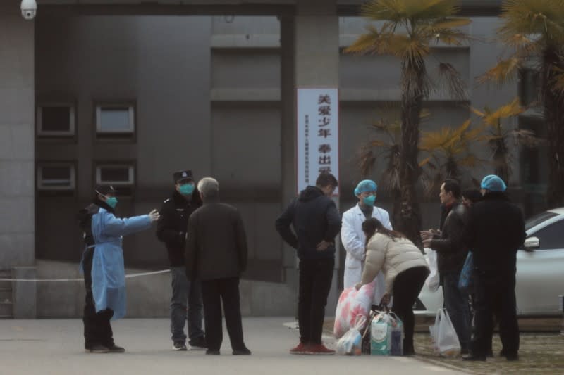 Medical staff and security personnel stop patients' family members from being too close to the Jinyintan hospital, where the patients with pneumonia caused by the new strain of coronavirus are being treated, in Wuhan