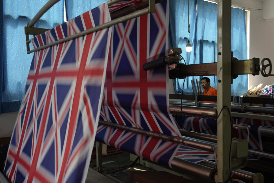 A worker produces British flags at the Shaoxing Chuangdong Tour Articles Co. factory in Shaoxing, in eastern China's Zhejiang province, Friday, Sept. 16, 2022. Ninety minutes after Queen Elizabeth II died, orders for thousands of British flags started to flood into the factory south of Shanghai. (AP Photo/Ng Han Guan)