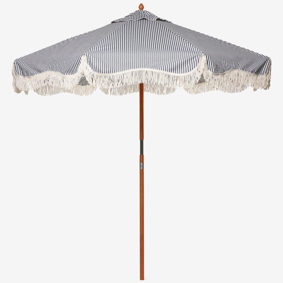 Striped blue and white patio umbrella with fringing