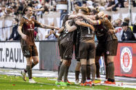 St. Pauli's players, including Jackson Irvine, right, celebrate after their teammate Marcel Hartel scored their side's third goal, during a second division, Bundesliga soccer match between St. Pauli and VfL Osnabrück, at the Millerntor Stadium, in Hamburg, Germany, Sunday, May 12, 2024. (Axel Heimken/dpa via AP)