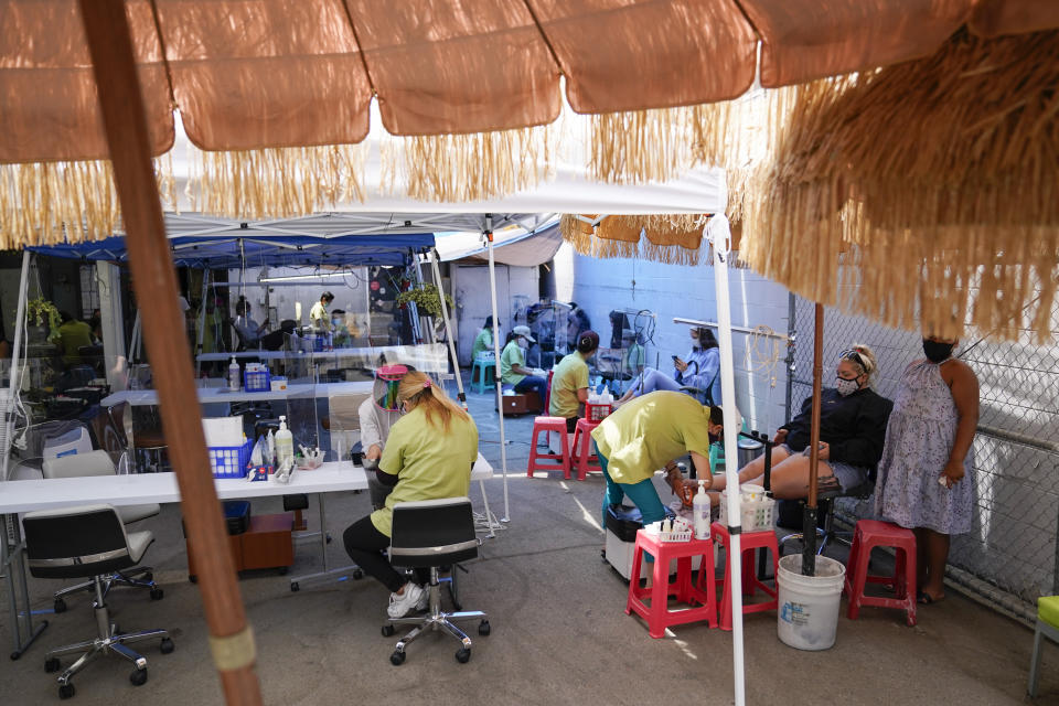 FILE - In this July 22, 2020 file photo, customers get their nails done outside Pampered Hands nail salon in Los Angeles. A steady drop in coronavirus cases across California cleared the way Tuesday, Sept. 22, 2020, for the wider reopening of businesses in nine counties, including much of the San Francisco Bay Area, the state's top health official said. Dr. Mark Ghaly, the state health secretary, said nail salons could also reopen with restrictions, though he cautioned that California's reopening must remain "slow and stringent" and residents cannot let their guard down as flu season arrives and cases rise in Europe and other parts of the U.S. (AP Photo/Ashley Landis, File)