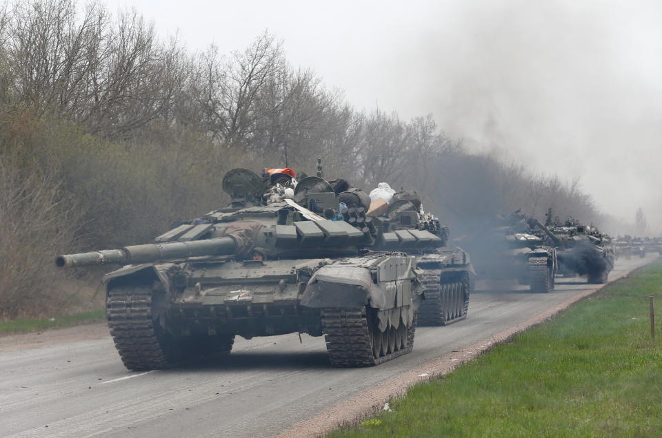A convoy of tanks moves down a road.