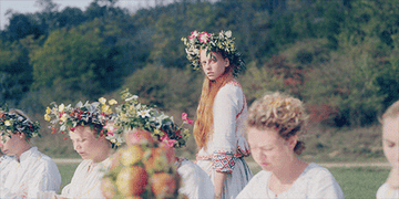 woman walking by a table full of people wearing flower crowns