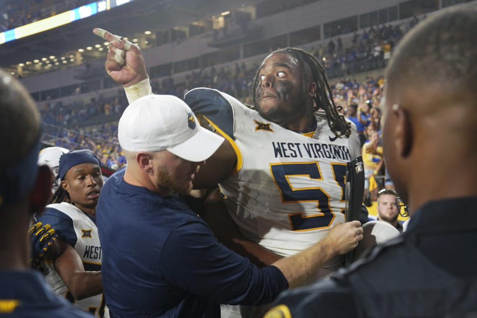 West Virginia defensive lineman Dante Stills (55) is pushed away from Pittsburgh players as the team leaves the field after an NCAA college football game Thursday, Sept. 1, 2022, in Pittsburgh. Pittsburgh won 38-31.(AP Photo/Keith Srakocic)