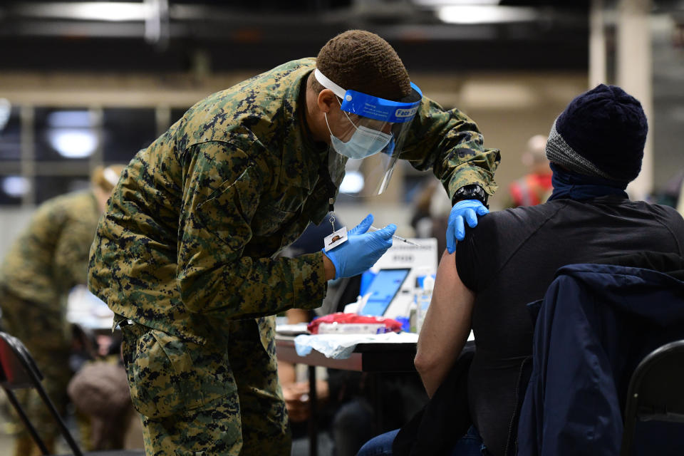 A member of the U.S. Armed Forces administers a dose of the Pfizer COVID-19 vaccine