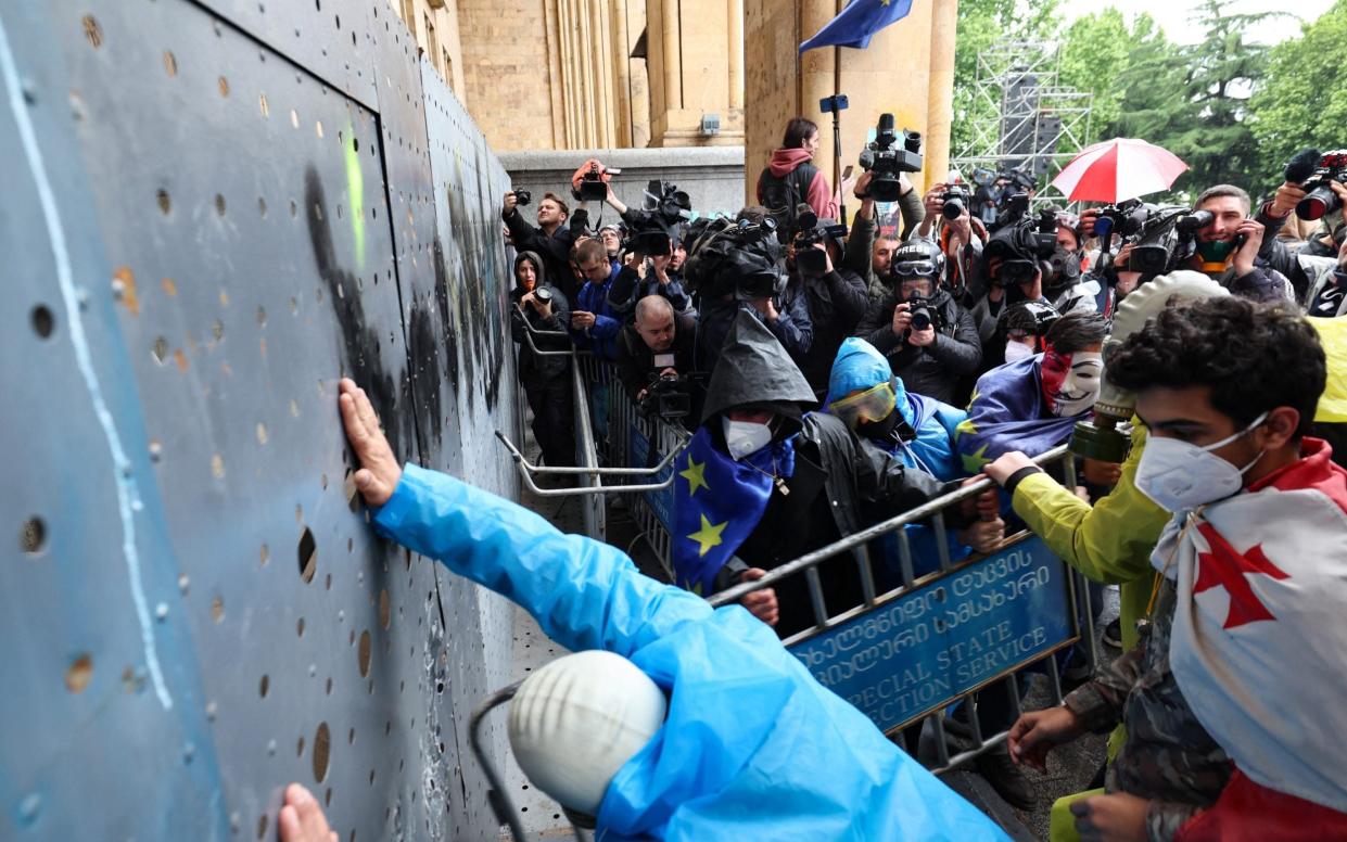 Georgian demonstrators attempt to break into the parliament through a metal barrier