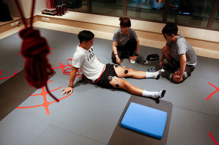 FILE PHOTO: Taiwanese Winter Olympic luge athtlete Lien Te-an talks to physiotherapists at a gym room in Taipei, Taiwan September 19, 2017. REUTERS/Tyrone Siu