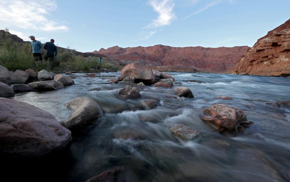 People walk along a narrow stretch of rushing water.