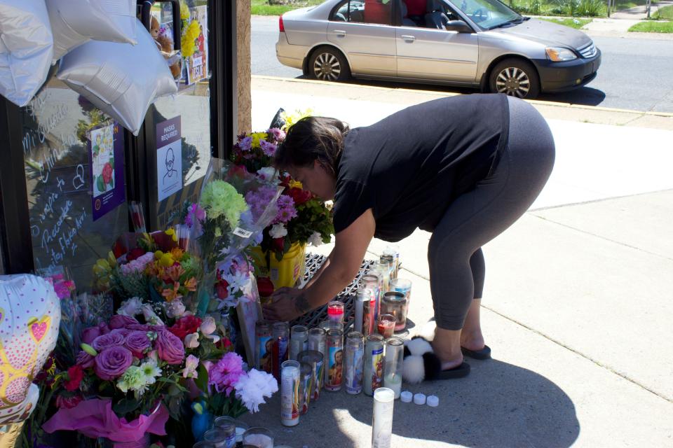 Damaris Roman lights a candle for Leslie Lizet Basilio at the entrance of the Metro by T-Mobile store in Elsmere on Tuesday, May 18, 2021.