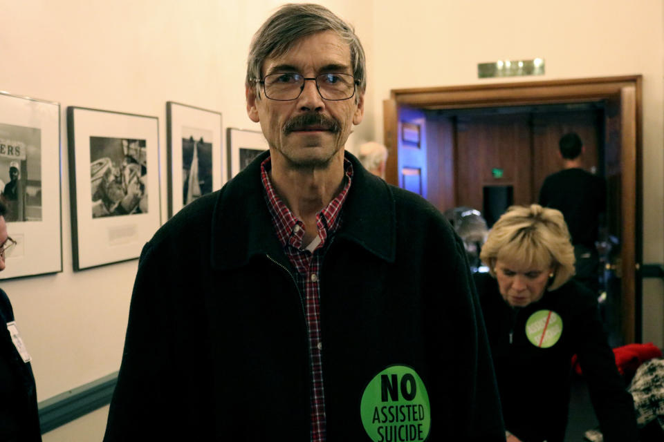 Paul Okerblom, of Salisbury, Md., stands outside a crowded hearing room with opponents of a measure that would allow the terminally ill to end their lives with the help of a doctor, during a hearing in Annapolis, Md., on Friday, Feb. 15, 2019. (AP Photo/Brian Witte)