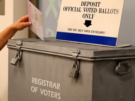 FILE PHOTO: A ballot is placed into a locked ballot box by a poll worker as people line-up to vote early at the San Diego County Elections Office in San Diego, California, U.S., November 7, 2016. REUTERS/Mike Blake/File Photo