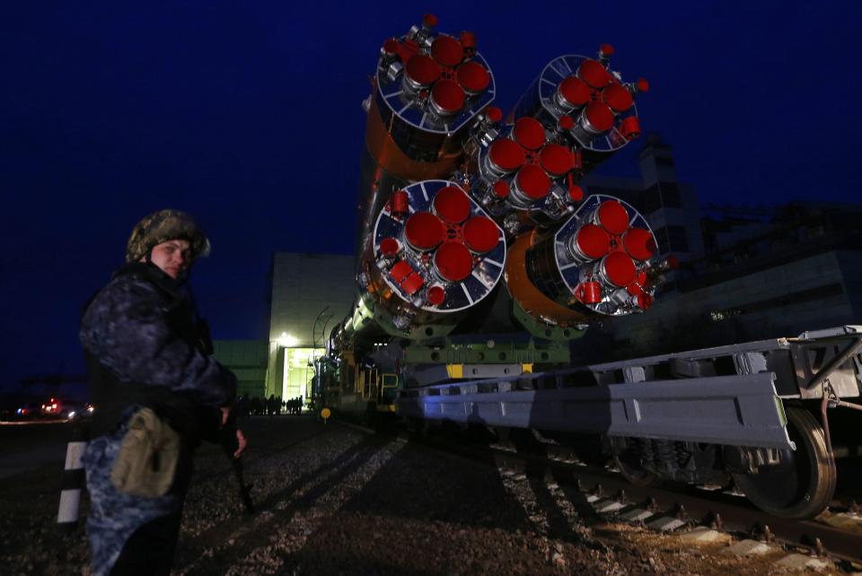 Armed policeman stands guard as the Soyuz TMA-12M spacecraft is transported from the assembling hangar to its launch pad at the Baikonur cosmodrom