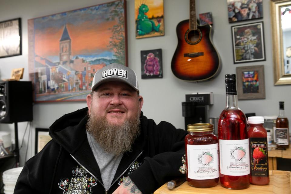 Rich Regal, owner of Modified Tattoo, sits by his new line of Regal Strawberry Glow Moonshine and Strawberry Glaze on January 11, 2024, in Lancaster, Ohio.